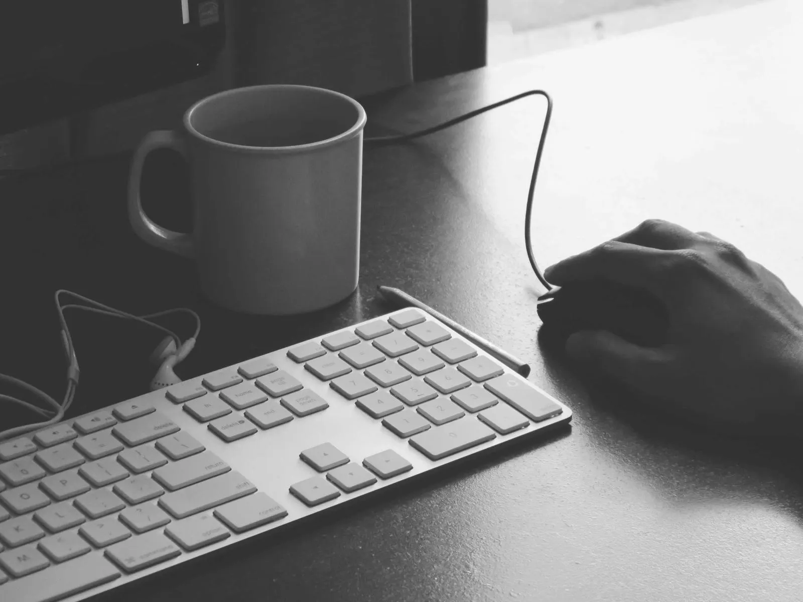 دست توسعهدهنده روی موس کنار کیبورد و فنجان قهوه در حال نوشتن Dockerfile