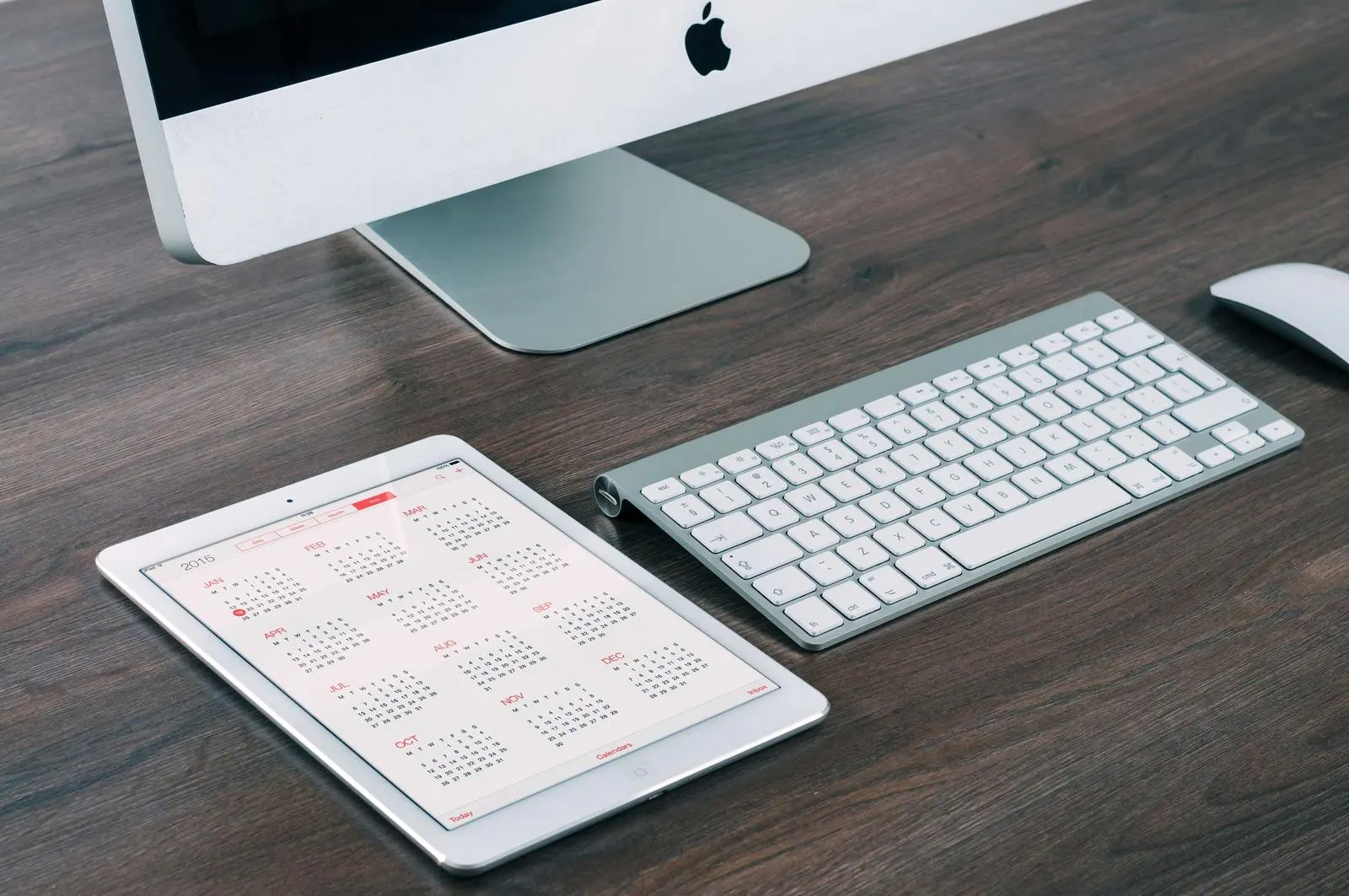 مانیتور iMac، کیبورد بیسیم و تبلت روی میز چوبی؛ یک اپلیکیشن برای همهی سیستمعاملهای دسکتاپ